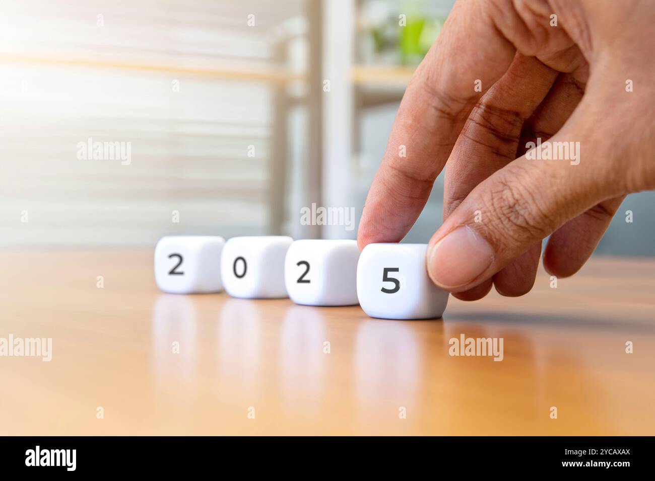 Closeup image of hand arrange a white cube with the number 2025. New year concept. Stock Photo