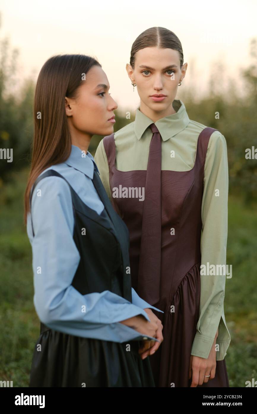 Two stylish girls in dresses with ties in the summer garden. Fashion ...