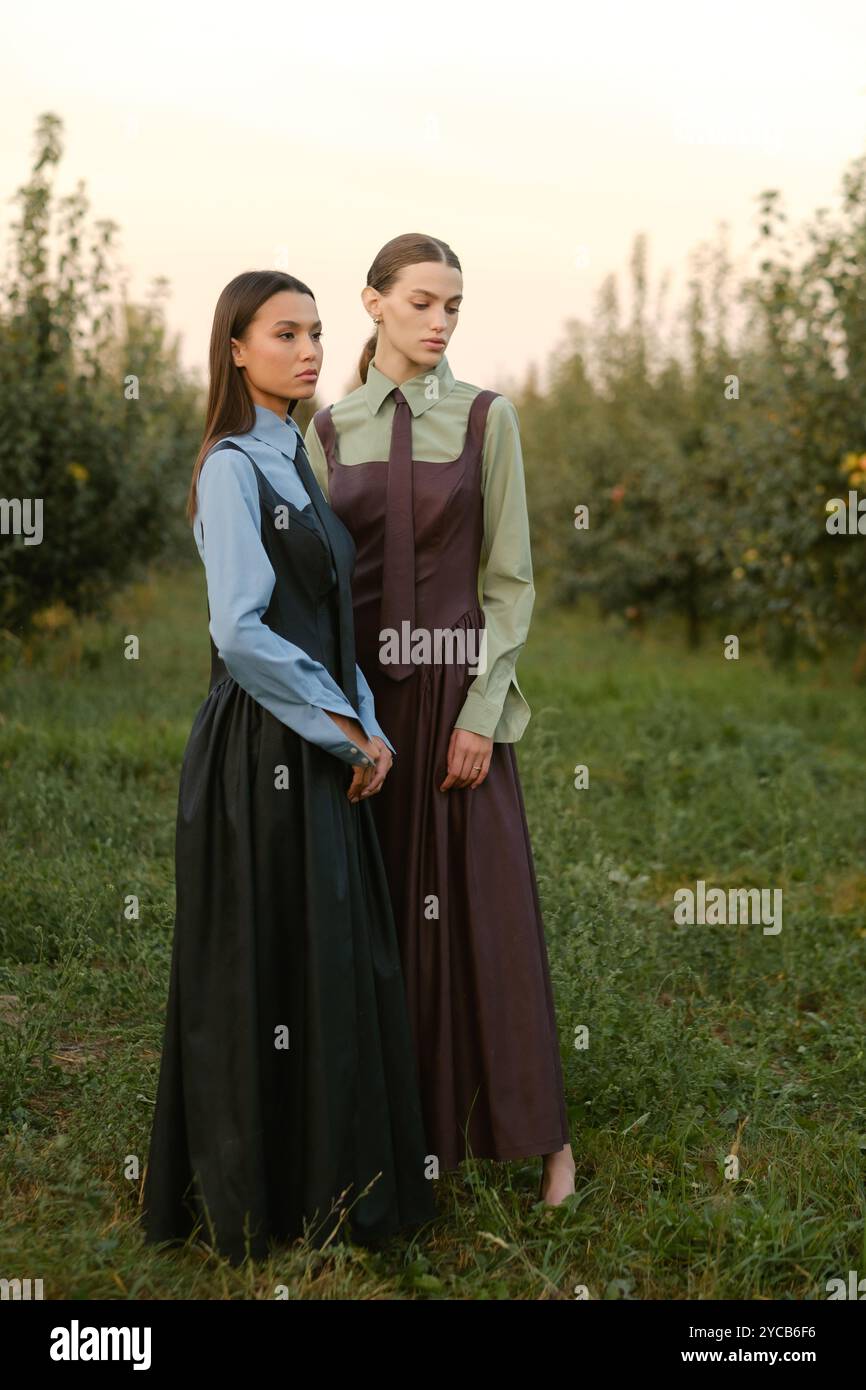 Two stylish girls in dresses with ties in the summer garden. Fashion ...