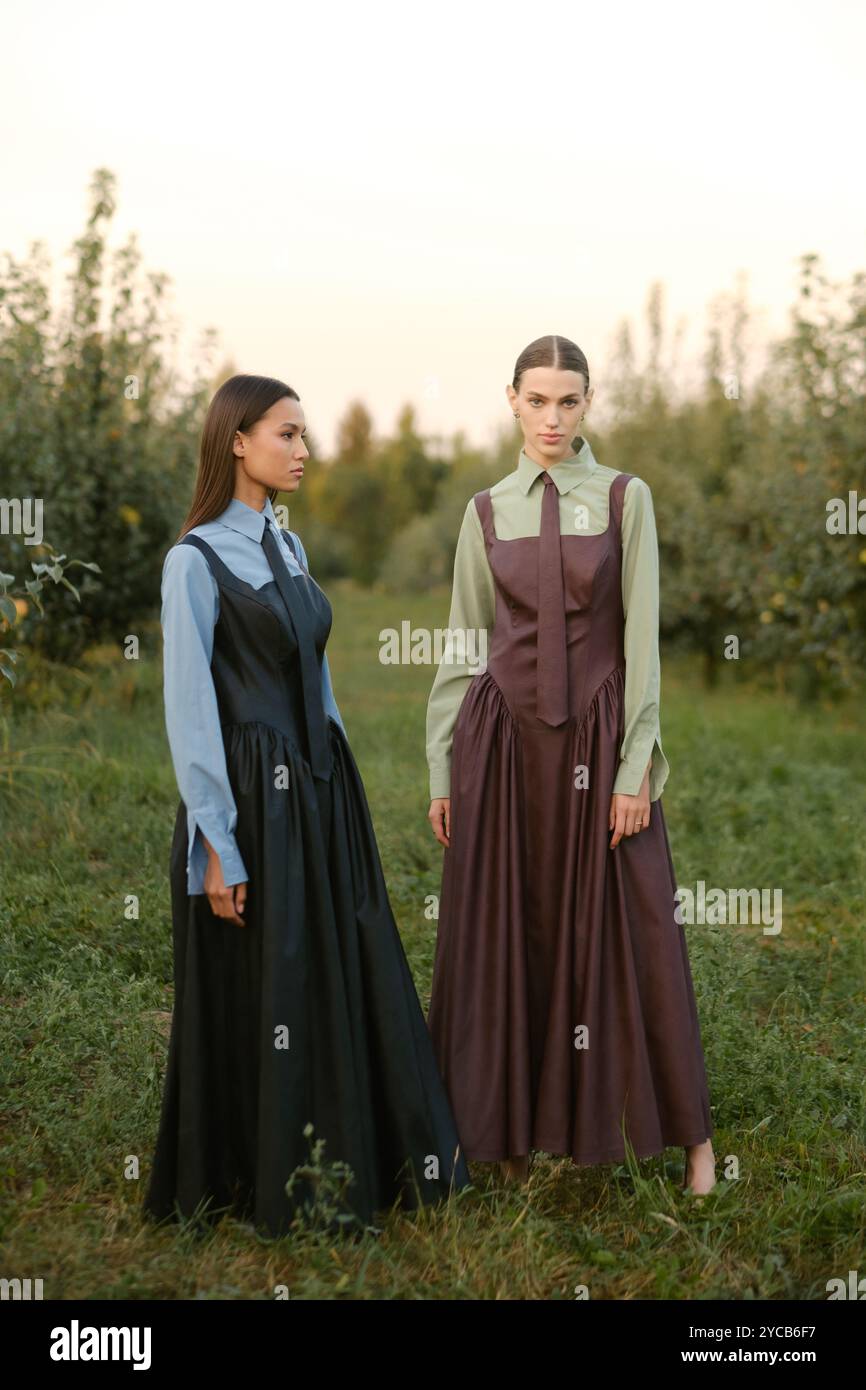 Two stylish girls in dresses with ties in the summer garden. Fashion ...