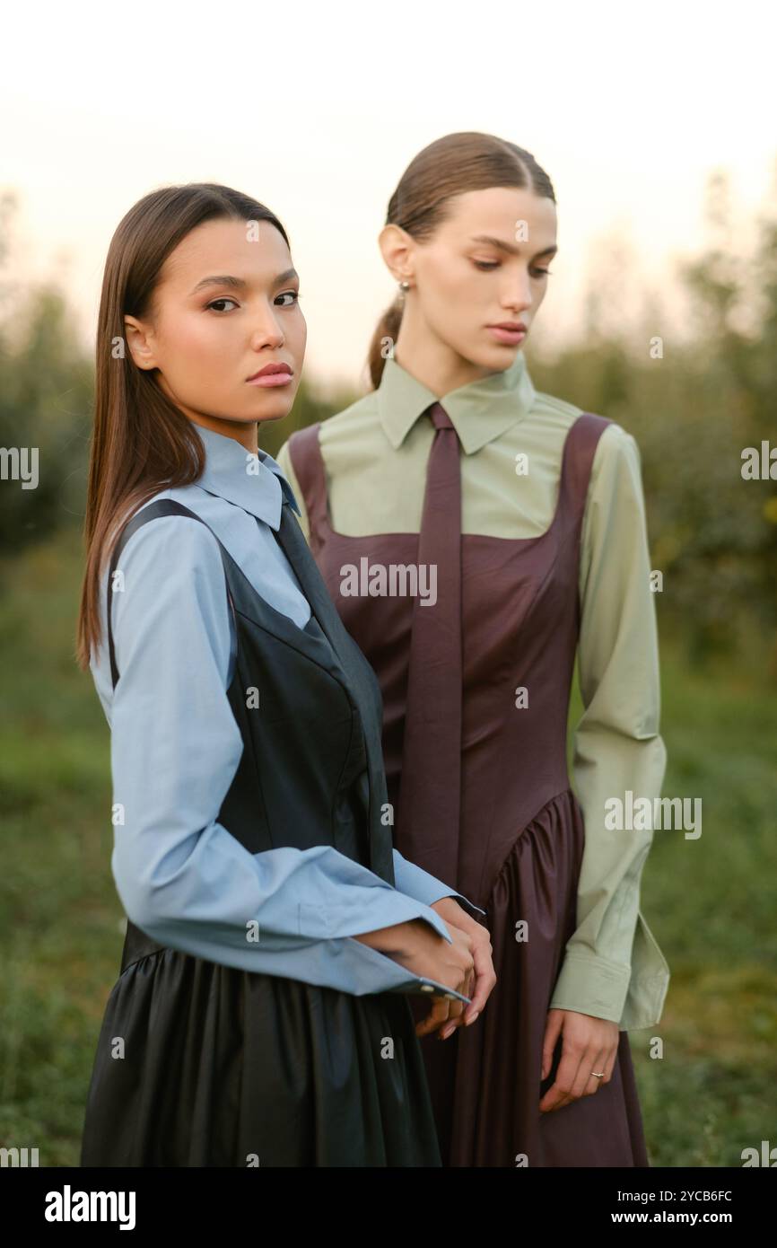 Two stylish girls in dresses with ties in the summer garden. Fashion ...