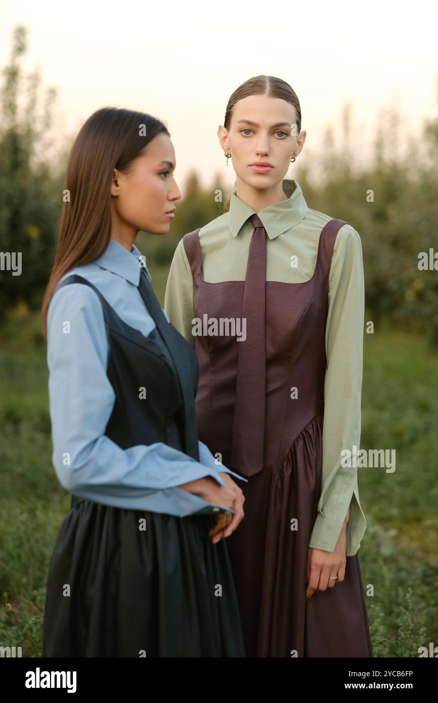 Two stylish girls in dresses with ties in the summer garden. Fashion ...