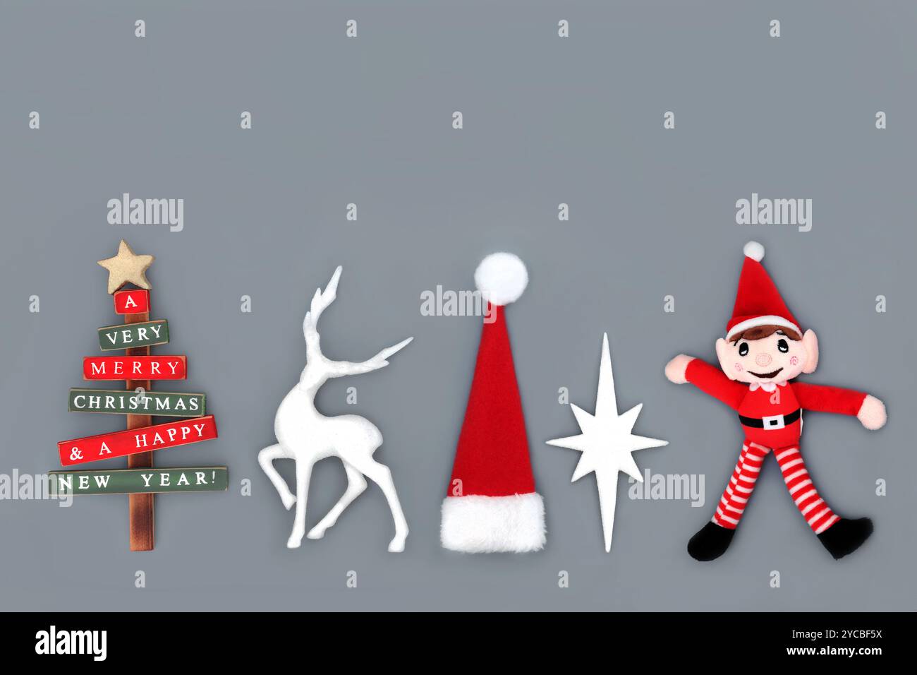 Symbols of Christmas Eve for the holiday season background on gray. Tree, reindeer, santa hat, star, elf festive bauble decorations. Stock Photo