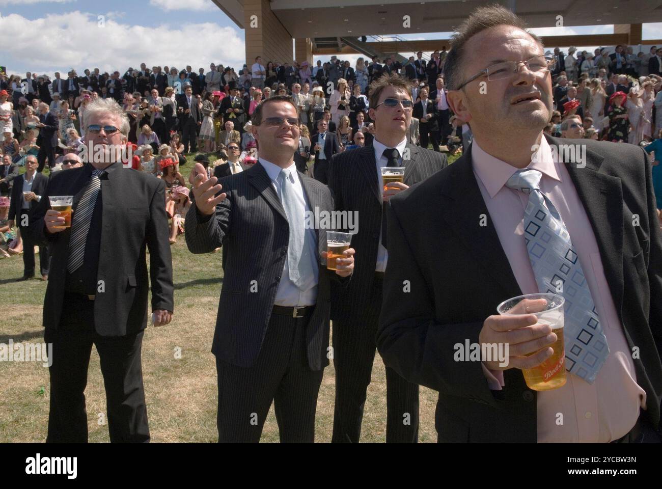 Group of men drinking beer watching the horses running in the Public Stands at Royal Ascot. Wearing suit and tie smartly dressed a day off work. Berkshire England 2006 2000s UK HOMER SYKES Stock Photo