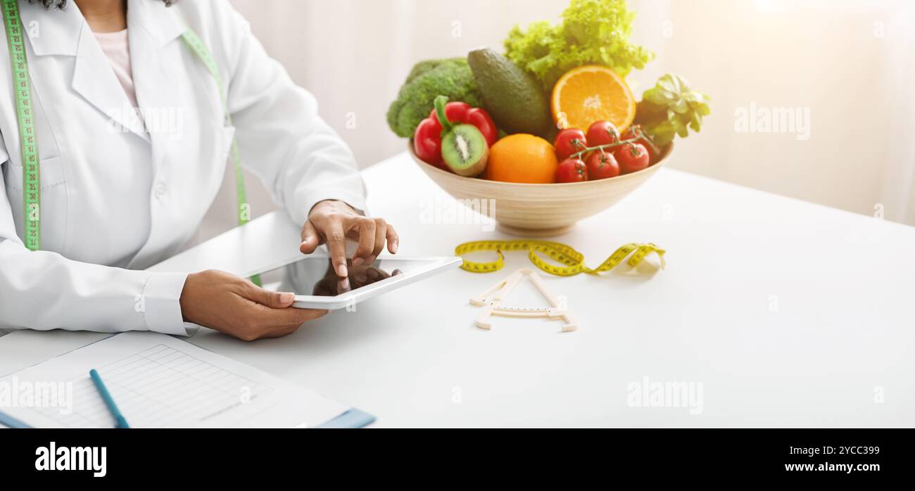 Dietologist black woman using digital tablet at workplace Stock Photo