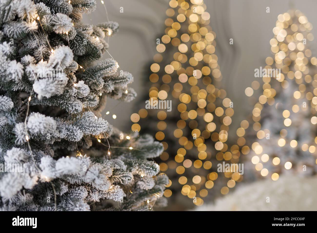 snowy fir tree close-up with garland and blurred lights in the background. New Year and Christmas celebration concept Stock Photo