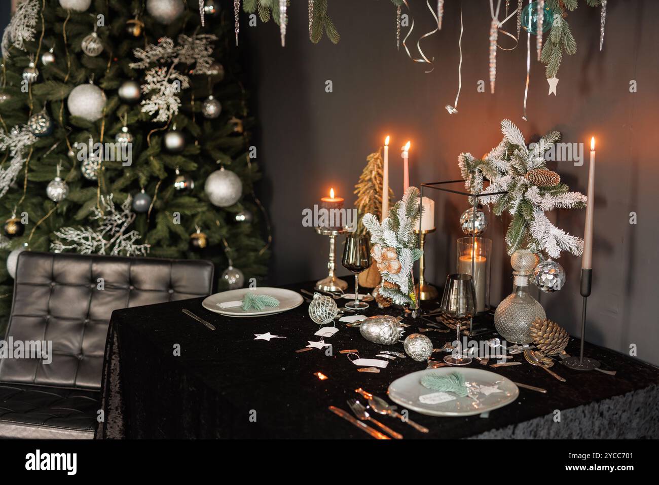 Christmas and New Year decorated with dark interior of the room. Festive Christmas night with candles on the table and beautiful dishes Stock Photo