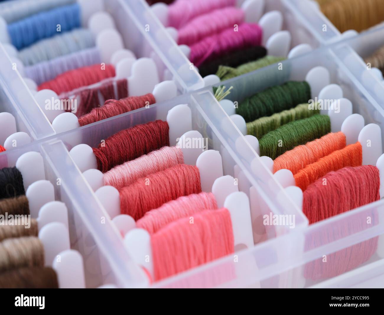 Plastic sorting box full of bobbins with different colour embroidery threads. Closeup Stock Photo