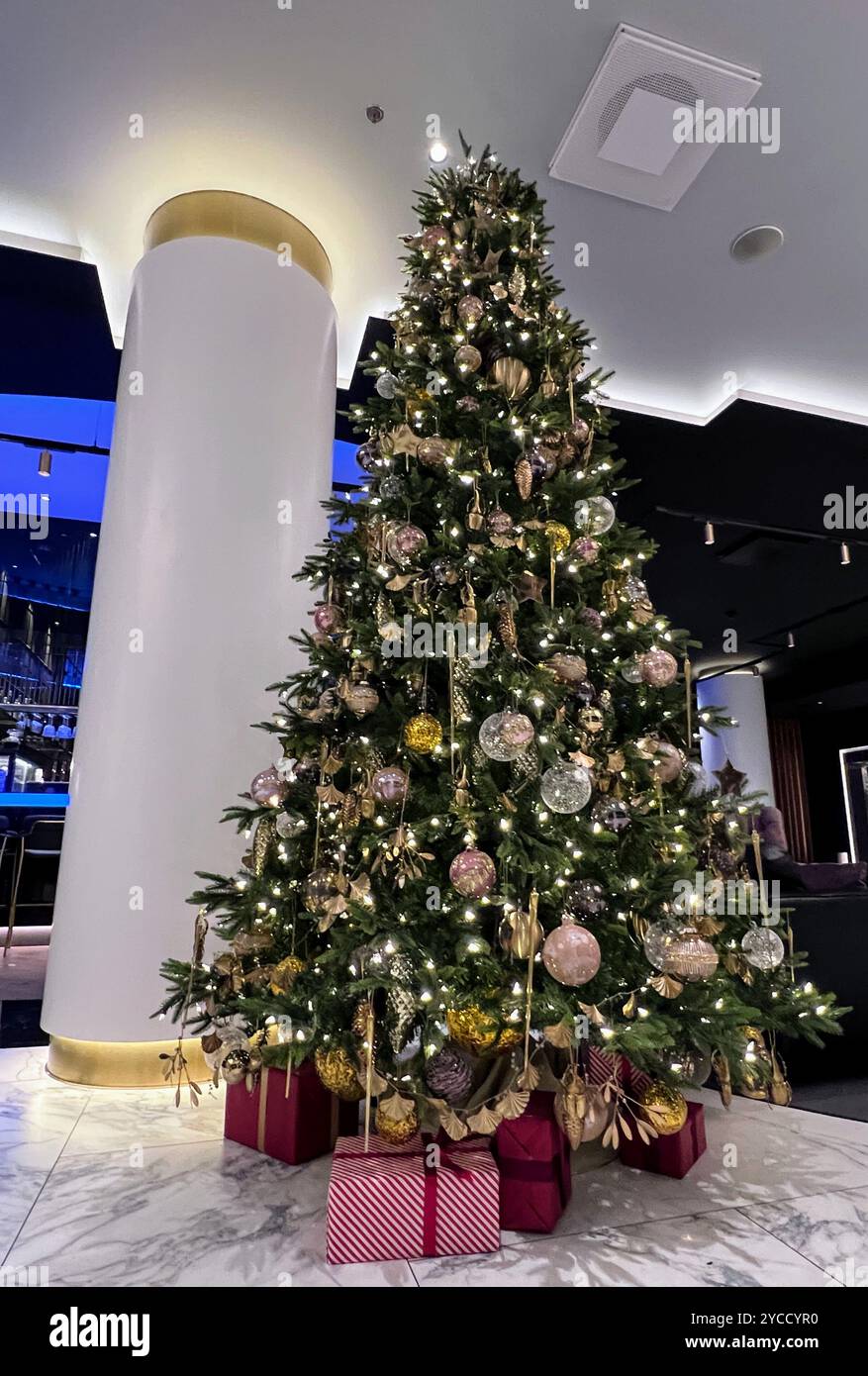 A beautifully decorated Christmas tree stands tall in a festive indoor setting. - Smartphone Captured Stock Image