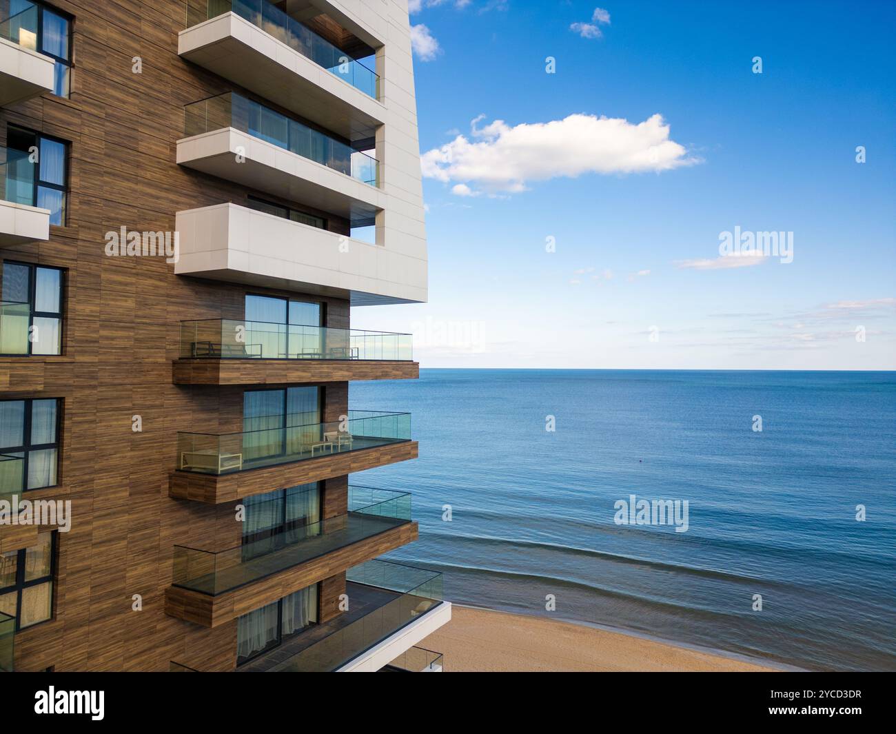 A modern beachfront apartment building with glass balconies overlooks a ...