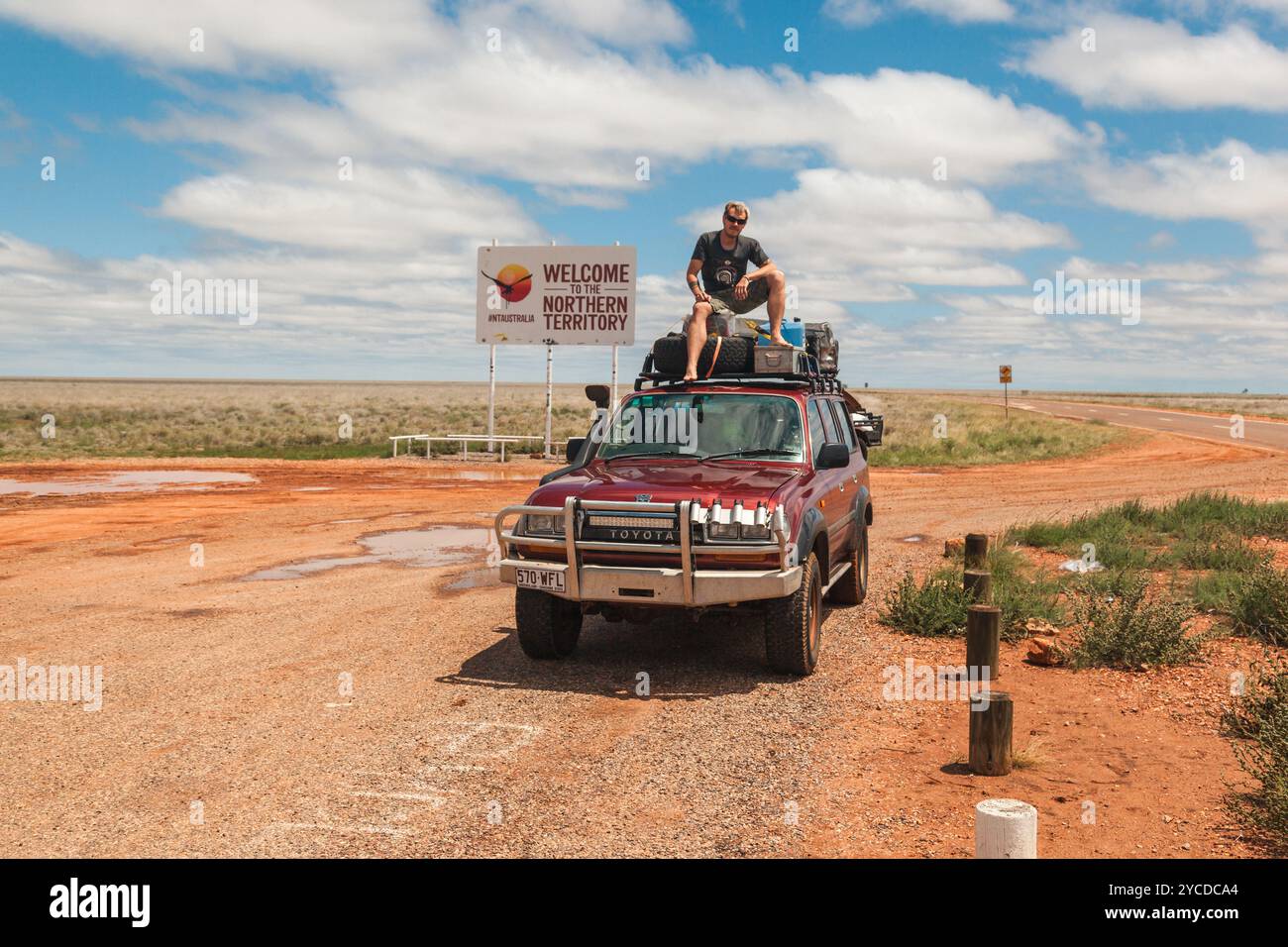 Travelers cheer on top of their vehicle after reaching the Northern Territory, embracing the rugged Australian Outback. Stock Photo