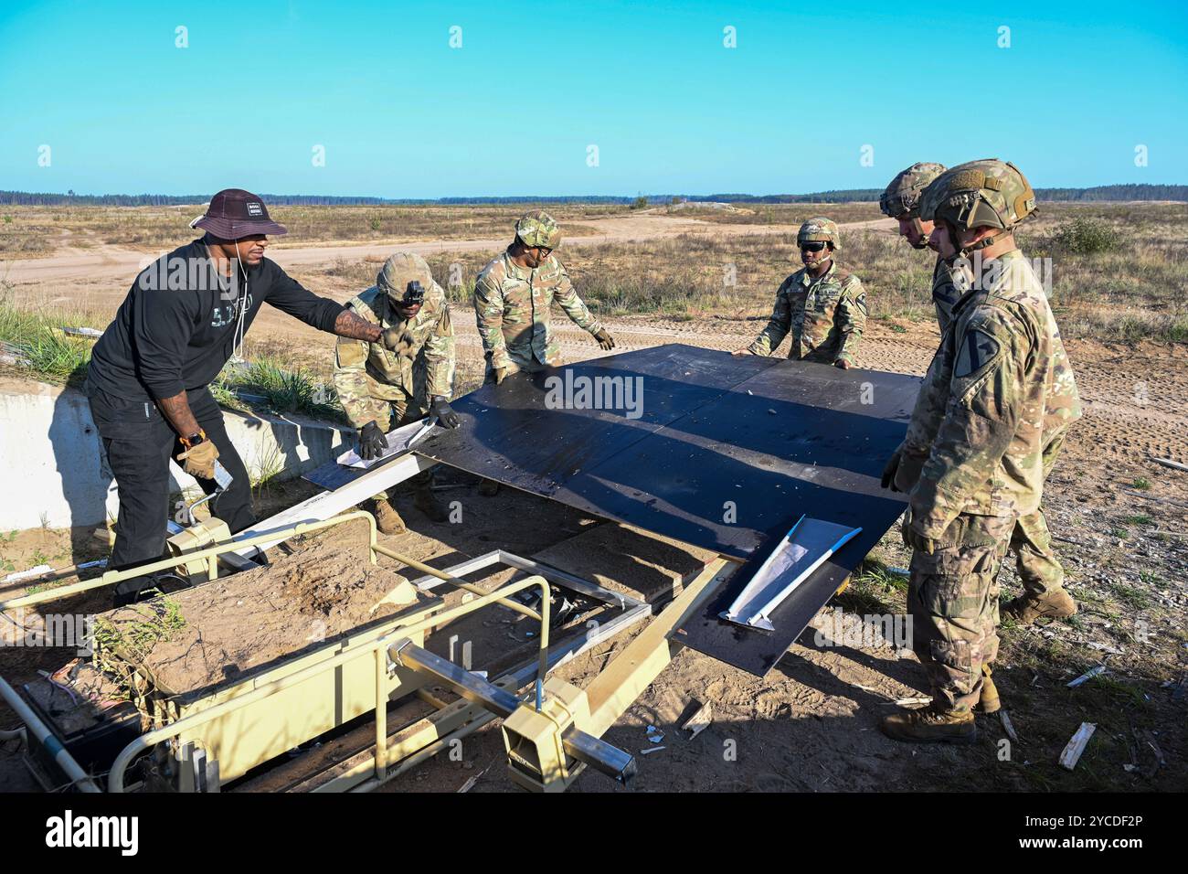 U.S. Soldiers assigned to 2nd Battalion, 8th Cavalry Regiment, 1st Armored Brigade Combat Team and Marcus Young site lead for Expeditionary Training Support Division, Training Support Activity Europe (TSAE), conduct maintenance repairs on targets at Training Area Pabrade, Lithuania, Sept. 19, 2024. TSAE routinely deploys expeditionary training support teams throughout Europe and Africa to meet U.S. and NATO forces’ training requirements. (U.S. Army photo by Sgt. Cody Nelson) Stock Photo