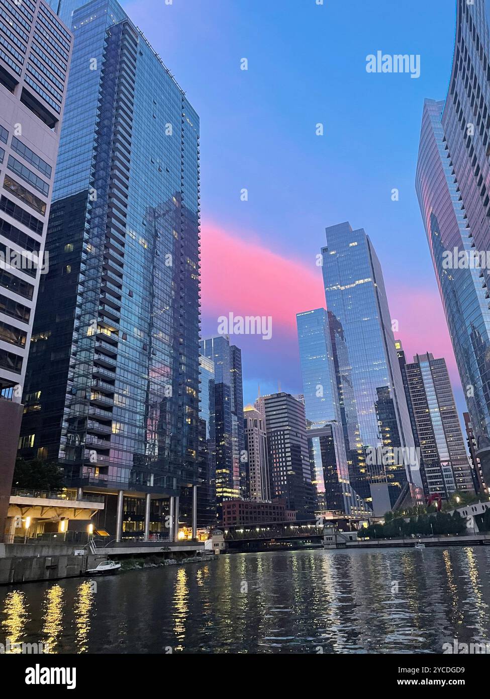 Chicago, IL, USA. Glass skyscrapers along Chicago's riverfront mirror the dramatic sunset, reflections dancing as coral skies paint the urban canvas. - Smartphone Captured Stock Image