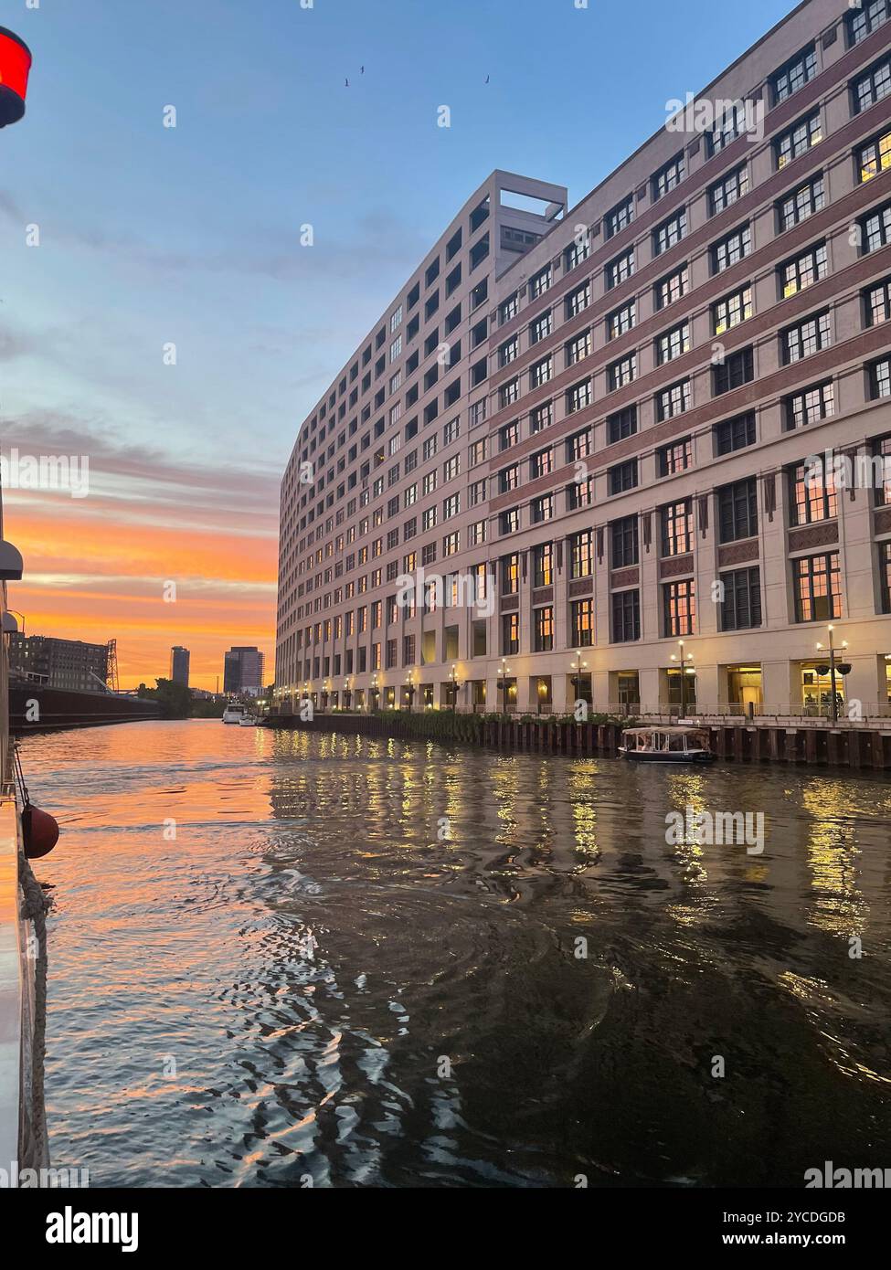 Art Deco grandeur curves along Chicago's riverfront, its windows ablaze with sunset's copper glow while rippling waters mirror the urban masterpiece. - Smartphone Captured Stock Image