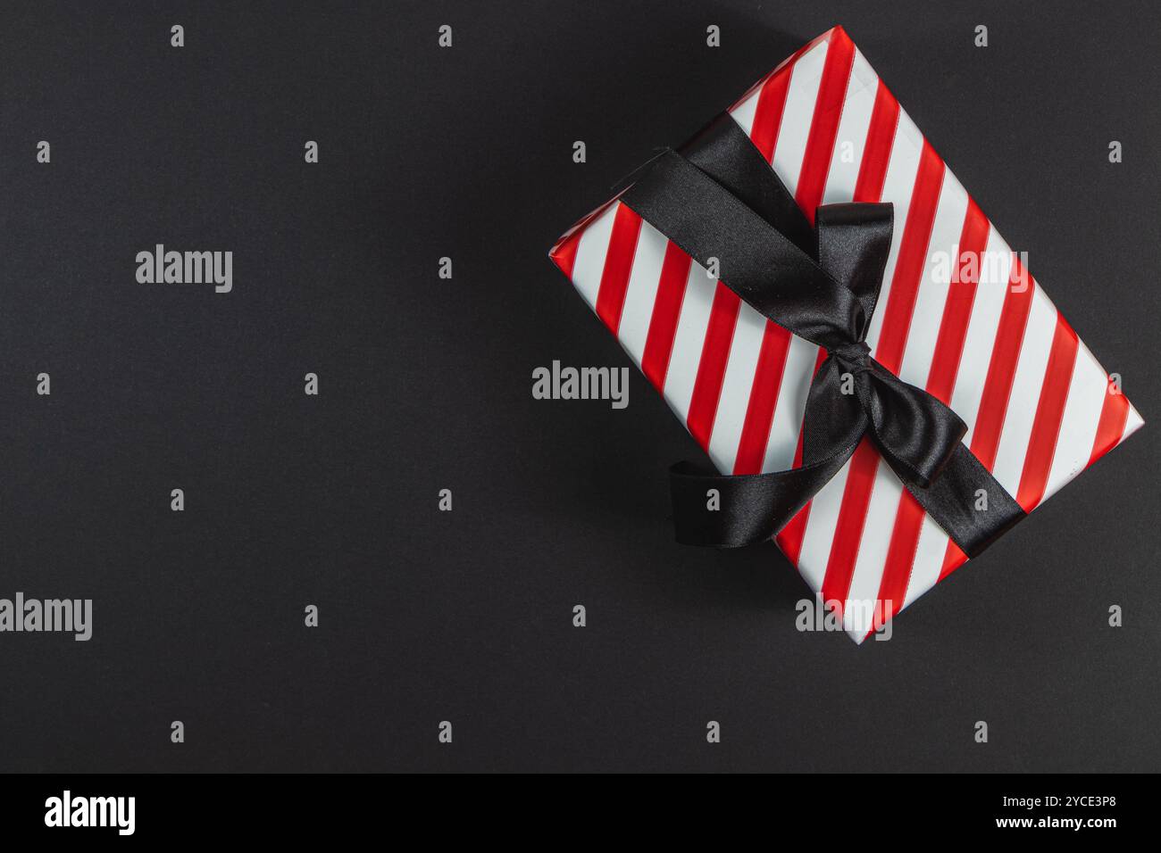 Red striped box with bow on black background for black friday new year Stock Photo