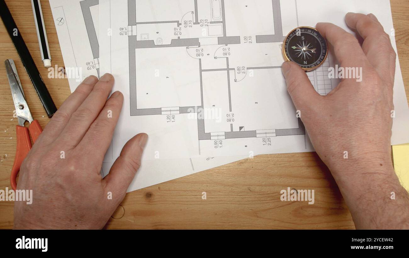 Top view, an architect's hand with a compass looks for the orientation ...