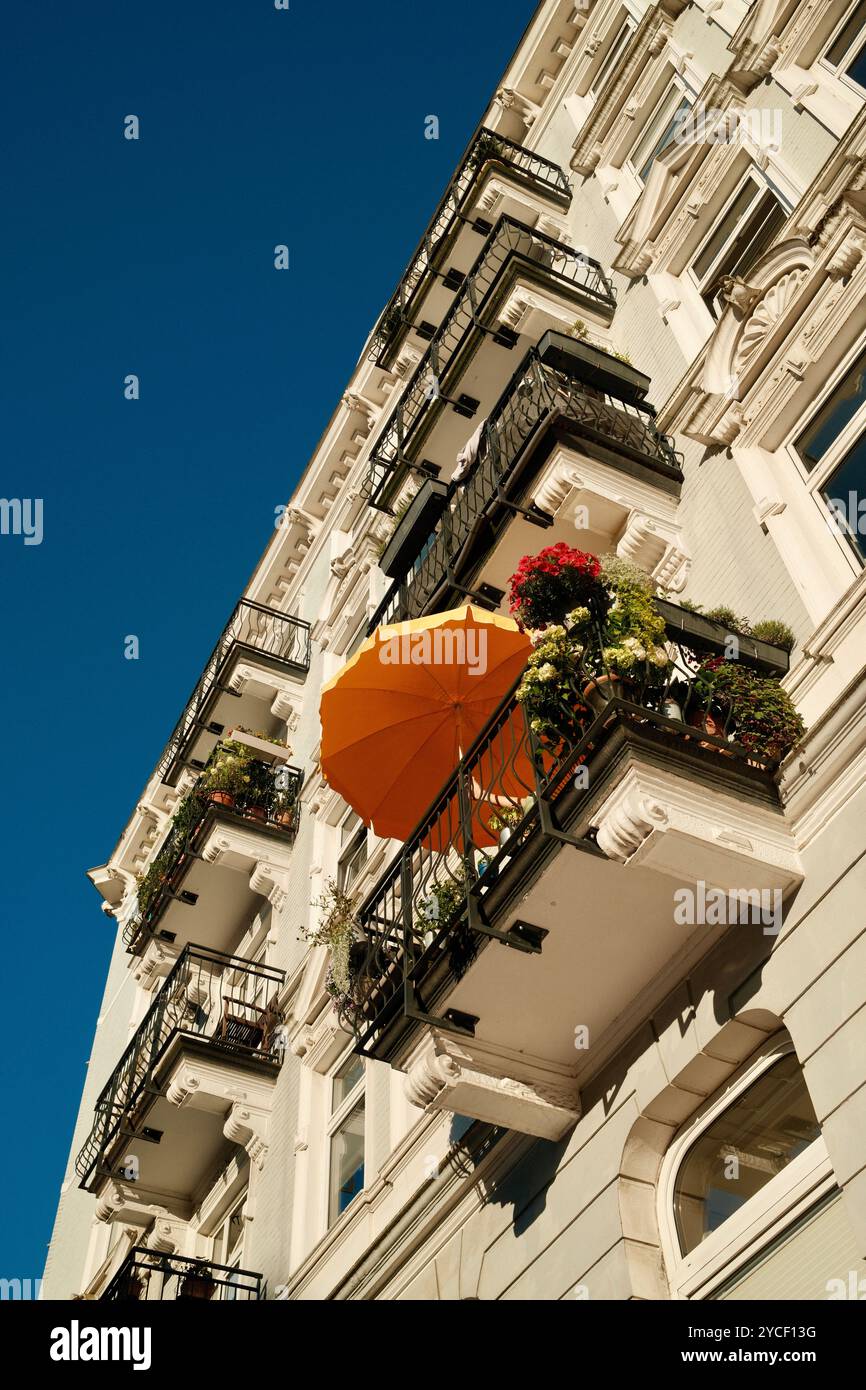 Altbau-Balkon mit sommerlicher Dekoration in Hamburg-Eppendorf. Gründerzeit-Fassade mit historischen Stuckelementen vor strahlend blauem Himmel. Stock Photo