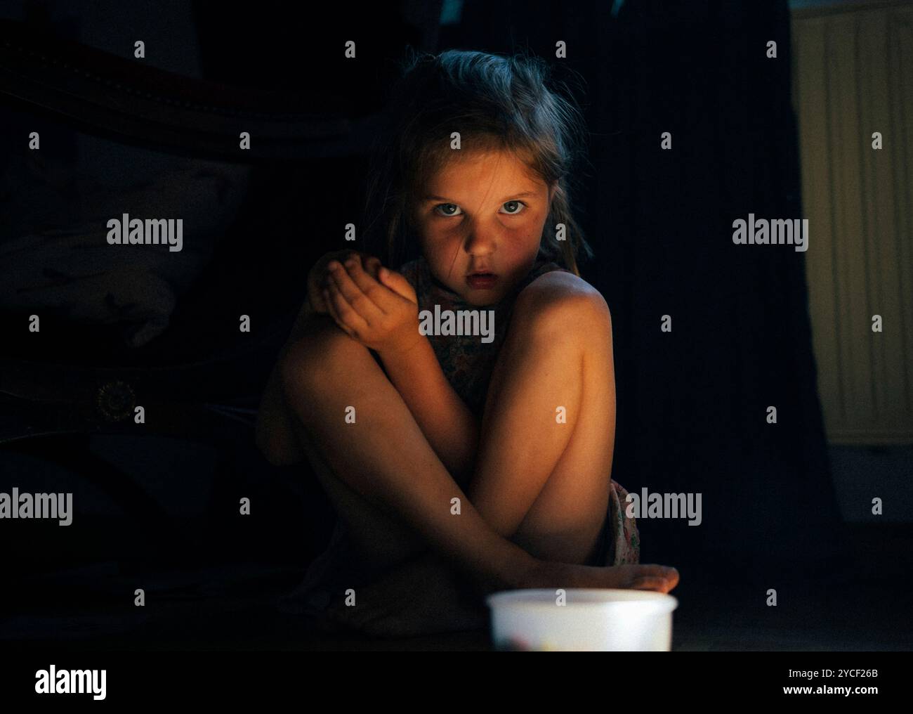 Girl sitting on the floor, looking into the camera Stock Photo