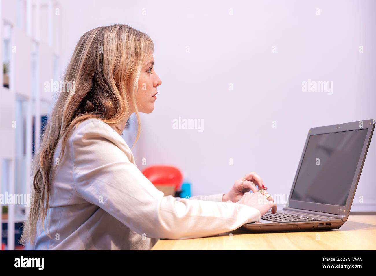 Focused woman working on laptop in modern office space Stock Photo