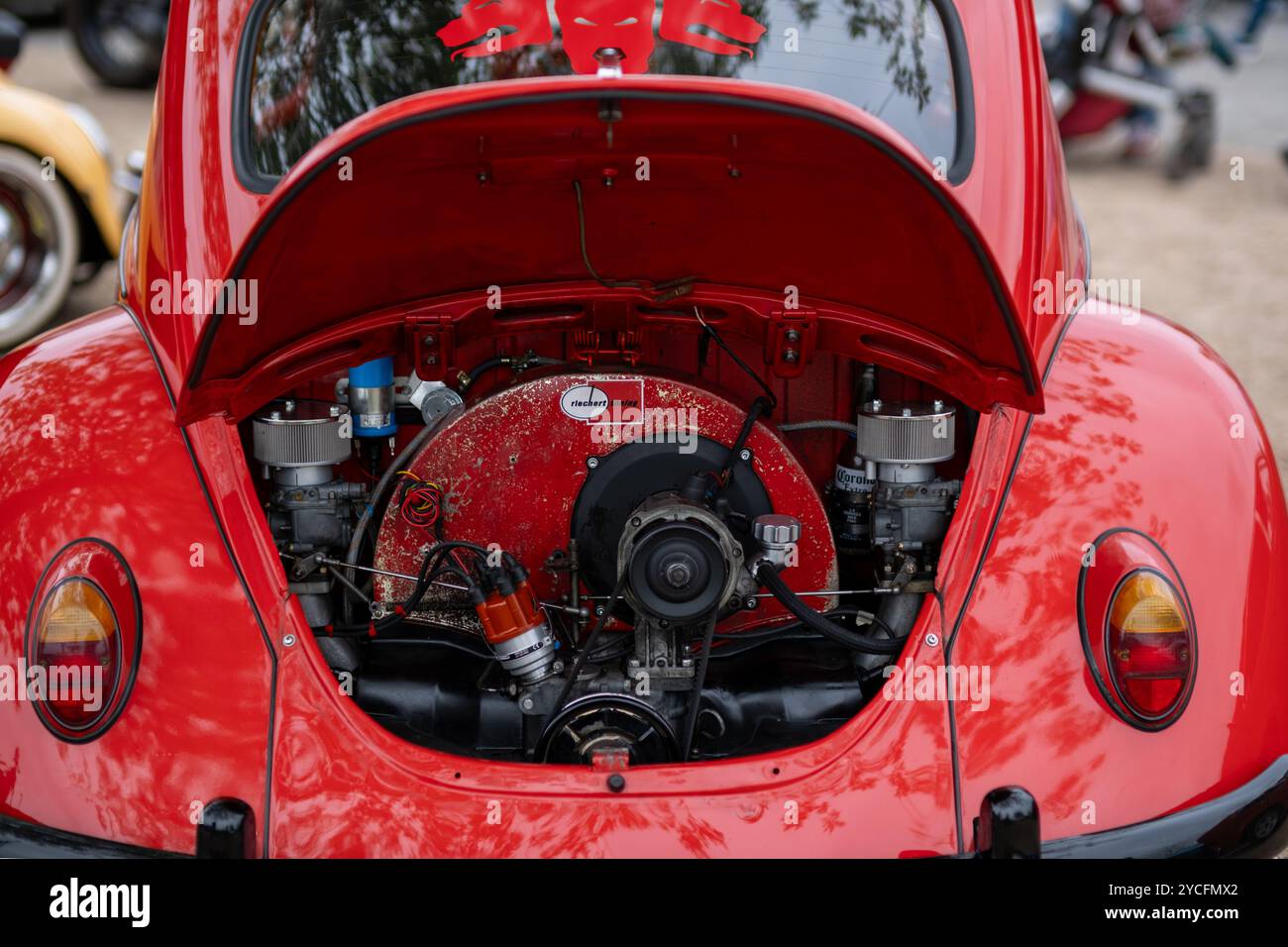 Detailed view of the engine compartment of a red VW Beetle, showcasing the classic air-cooled engine and aftermarket modifications. Stock Photo