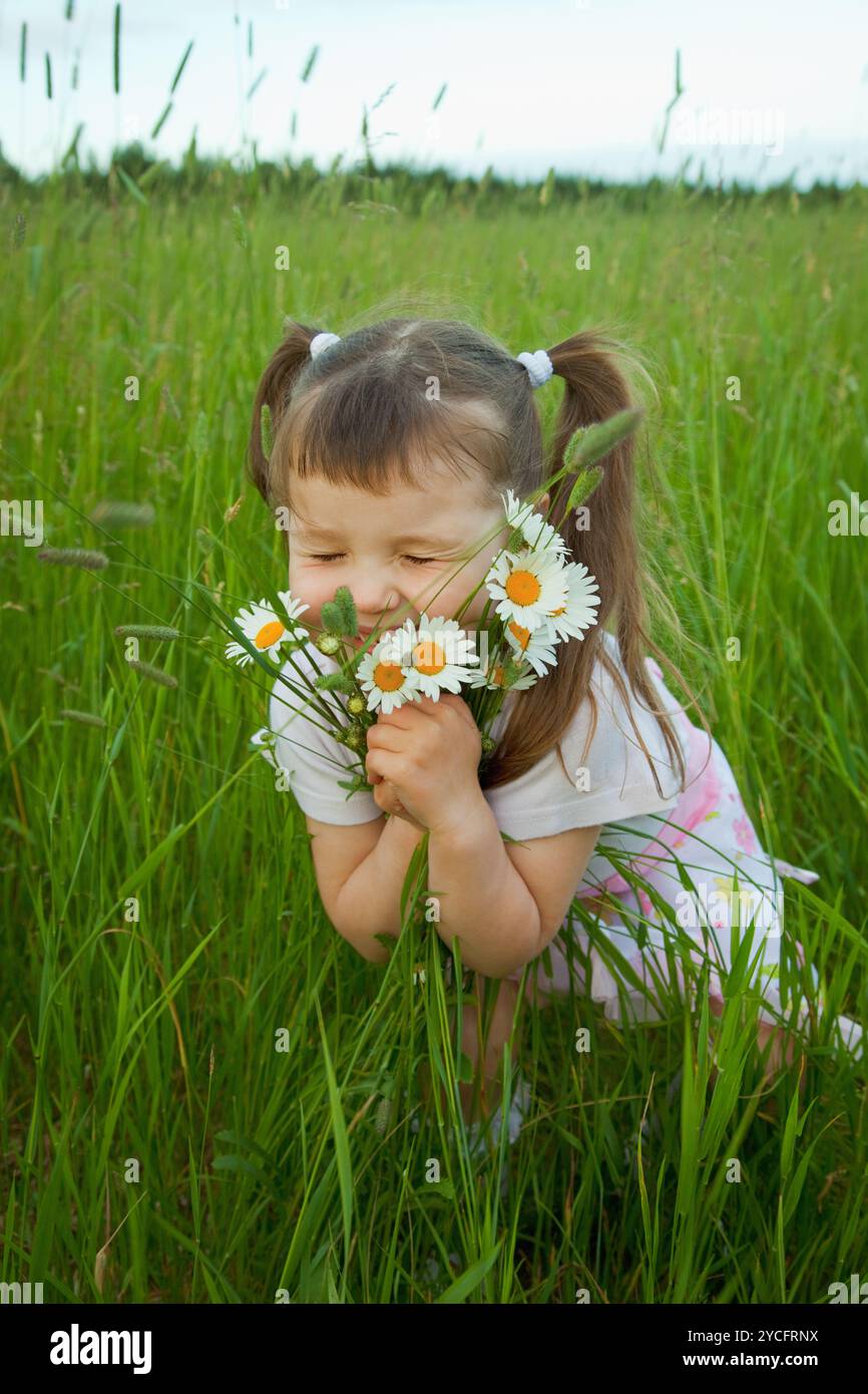 Little girl embraces flowers - chamomiles Stock Photo - Alamy