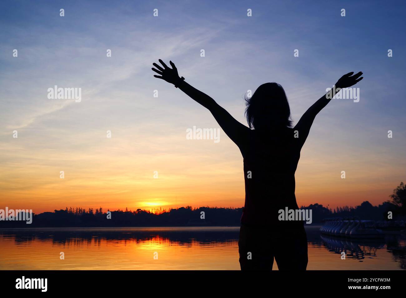 Silhouette of a woman raising arms to the beautiful sunrise Stock Photo ...