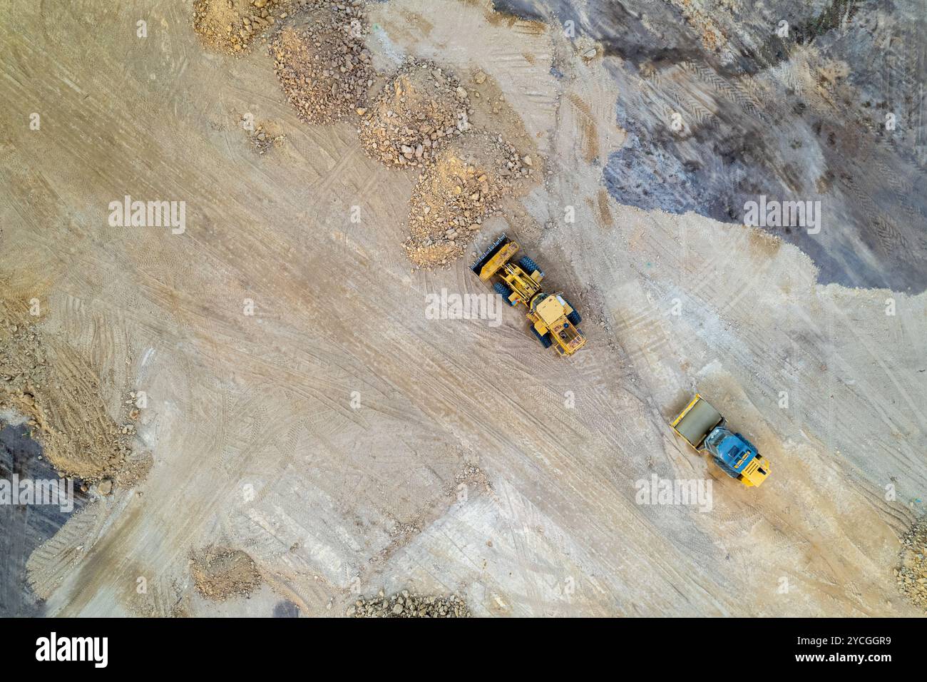 yellow tracked bulldozer performs earthworks on construction site, aerial view from a drone. Stock Photo