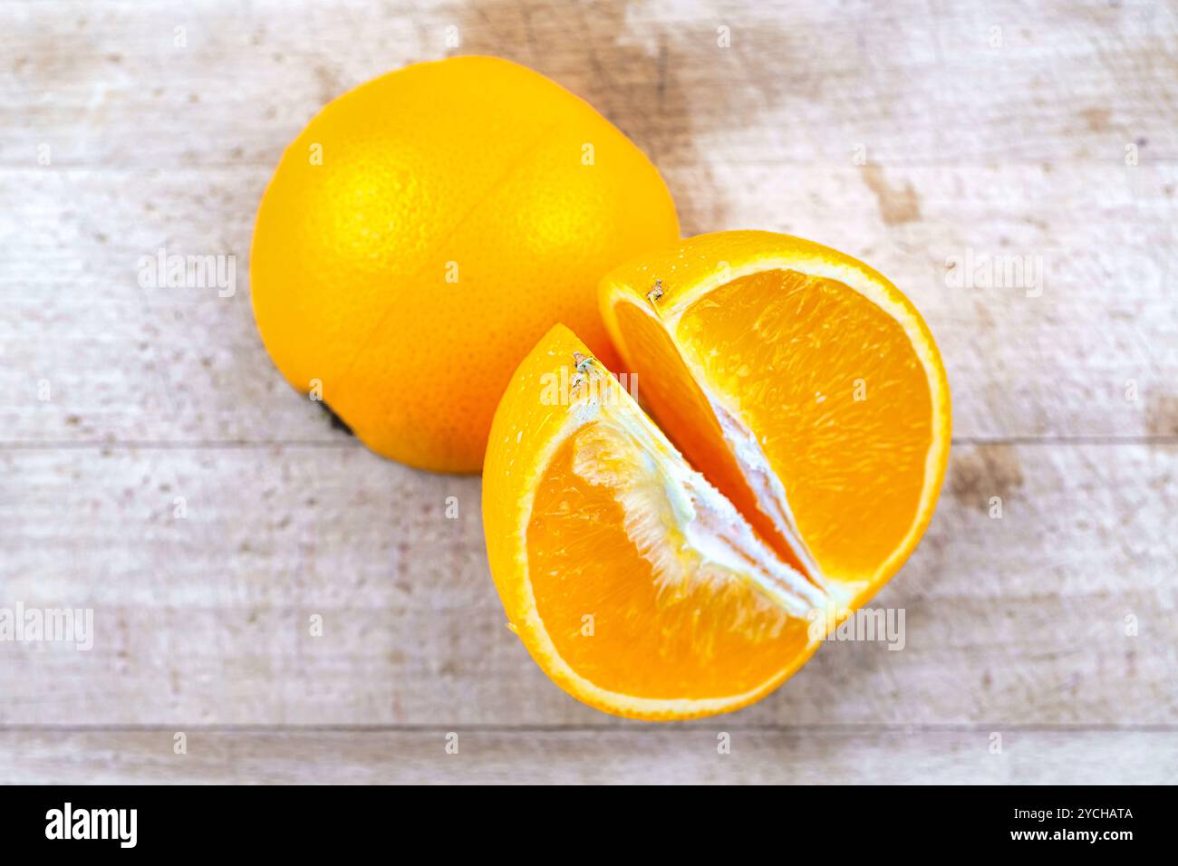Close-up of an orange fruit on a wooden cutting board. Stock Photo