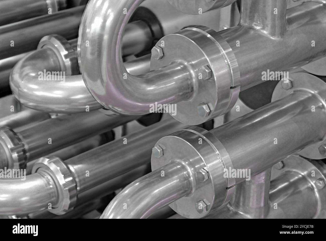 A lot of shiny curved stainless steel pipes of industrial equipment cooling system. Abstract industrial background. Stock Photo
