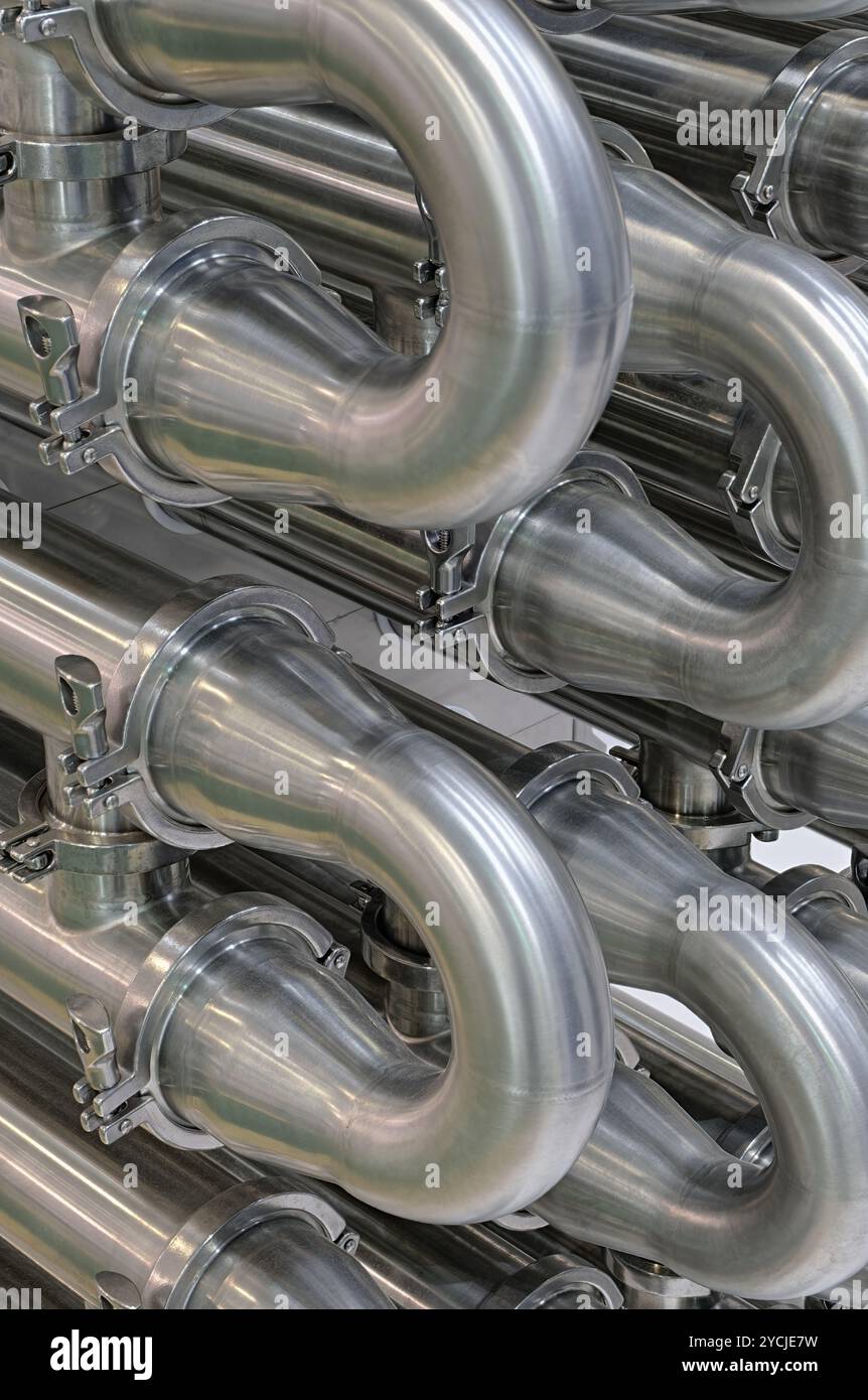 A lot of shiny curved stainless steel pipes of industrial equipment cooling system. Abstract industrial background. Stock Photo