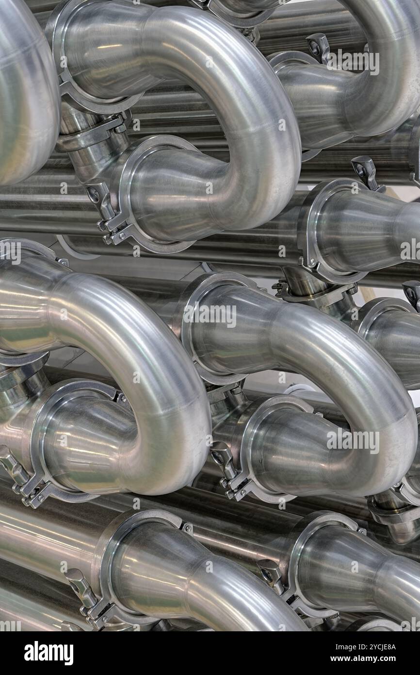 A lot of shiny curved stainless steel pipes of industrial equipment cooling system. Abstract industrial background. Stock Photo