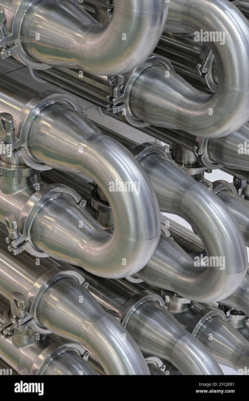 A lot of shiny curved stainless steel pipes of industrial equipment cooling system. Abstract industrial background. Stock Photo