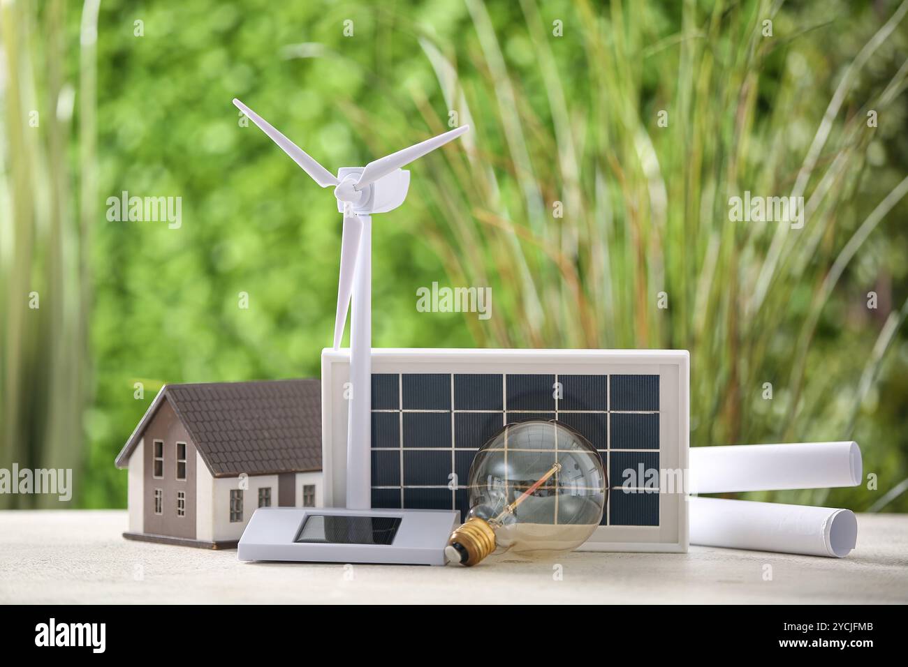 Wind turbine model, light bulb, house and solar panel on white table ...