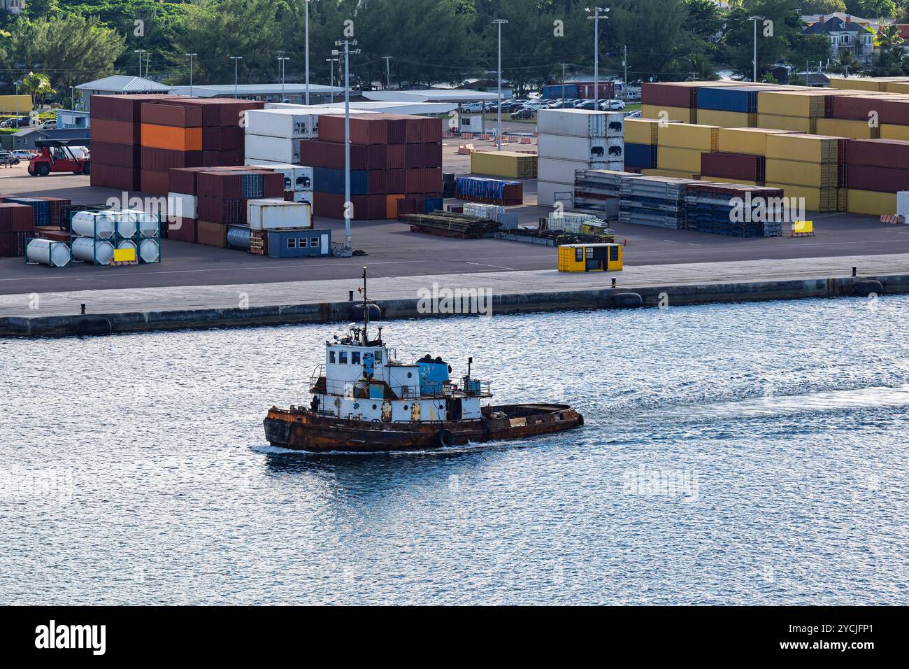 "A tugboat powers through the harbor, guiding vessels past towering