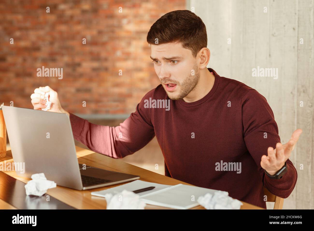 Emotional Worker Looking At Laptop Having Problem Sitting In Office Stock Photo