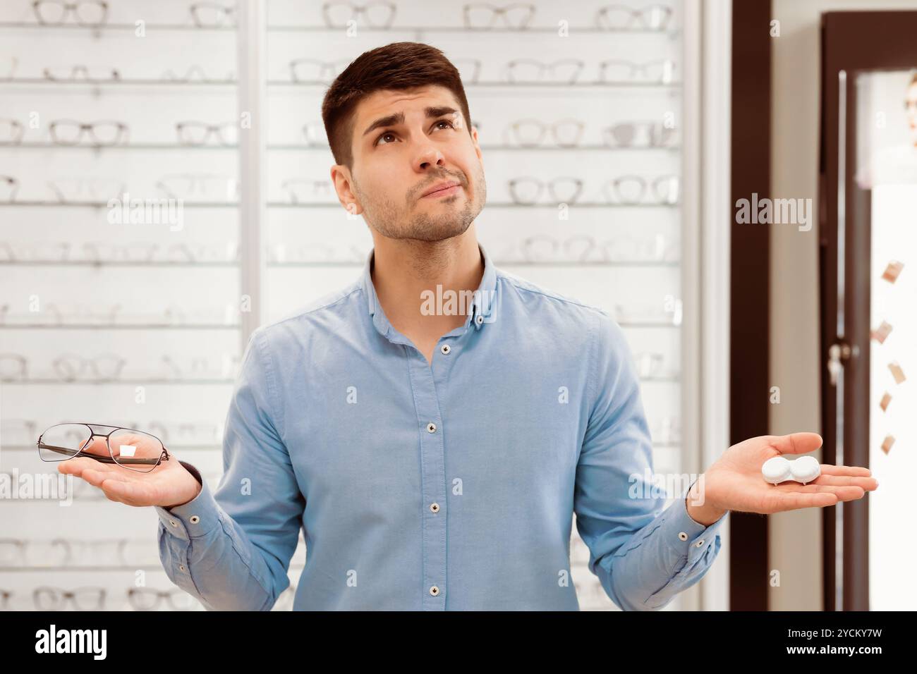 Pensive man choosing between eyeglasses and contacts Stock Photo