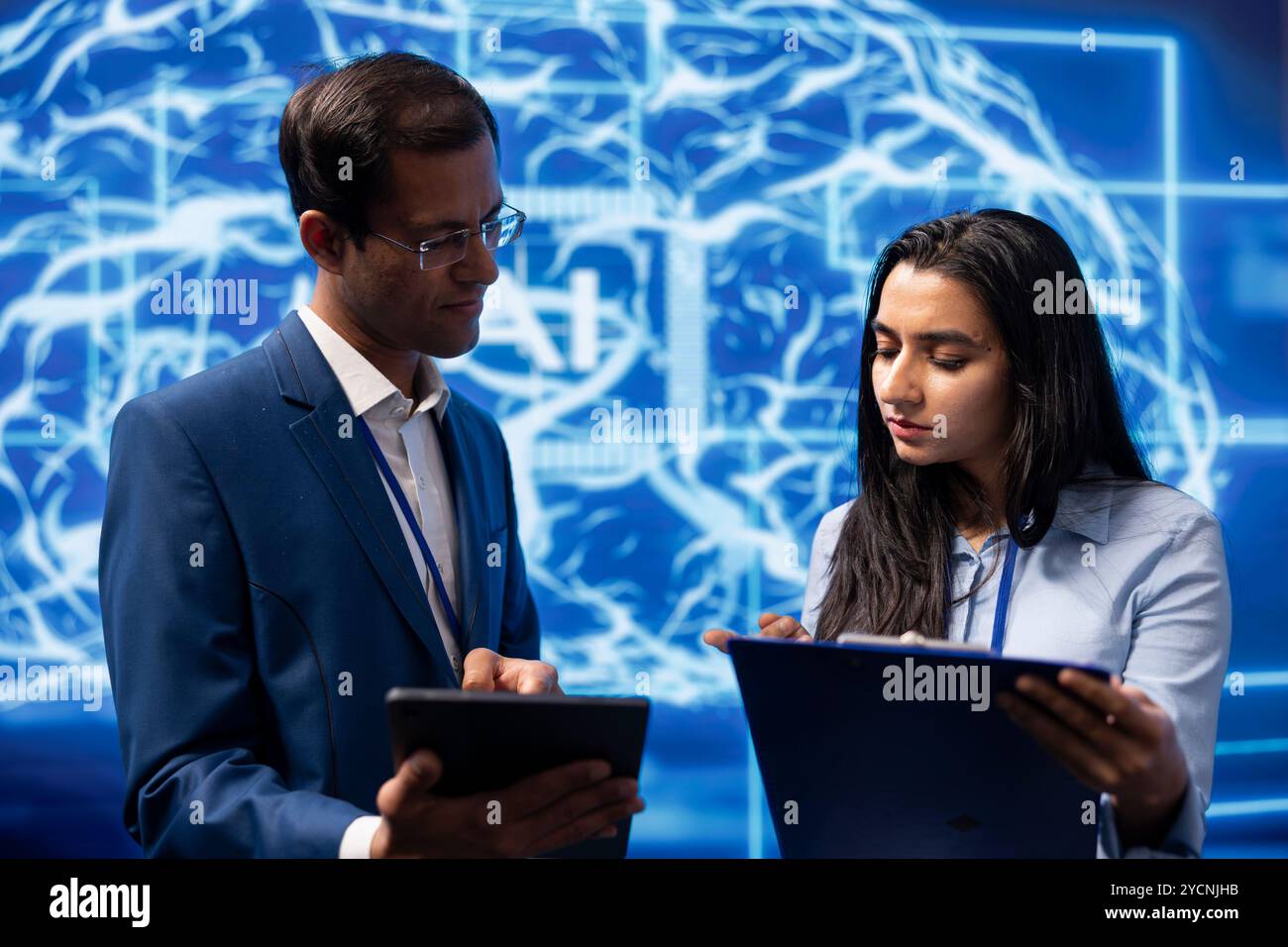 Technicians use AI cognitive computing to extract information from complex data on tablet. Employees at work using artificial intelligence technology, checking parameters Stock Photo