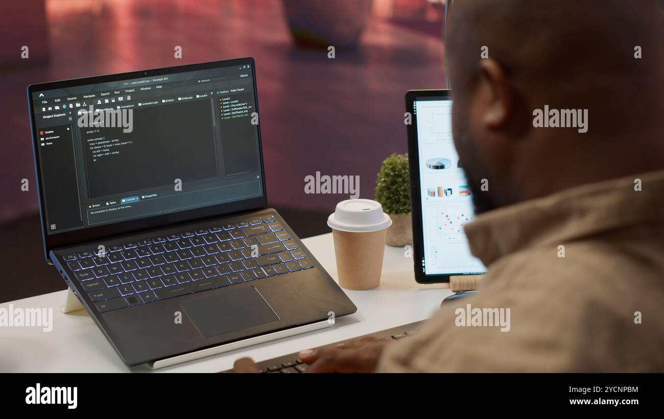 AI software developer creating an algorithm for deep learning and data mining, coding on his laptop at home office. Expert processing binary code on supercomputer neural network. Camera A. Stock Photo