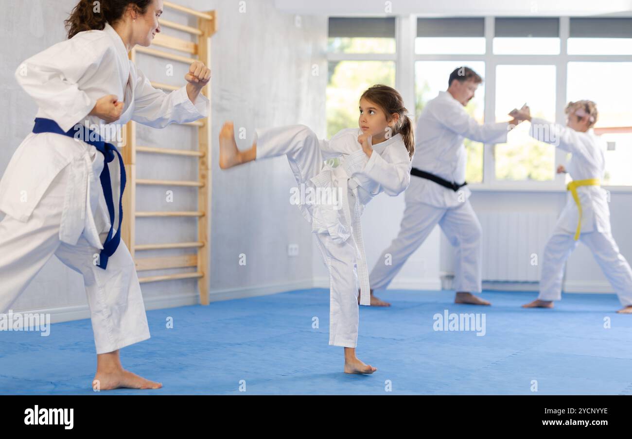 Preteen Girl In Kimono Practicing Karate Kicks During Sparring With preteen-girl-in-kimono-practicing-karate-kicks-during-sparring-with