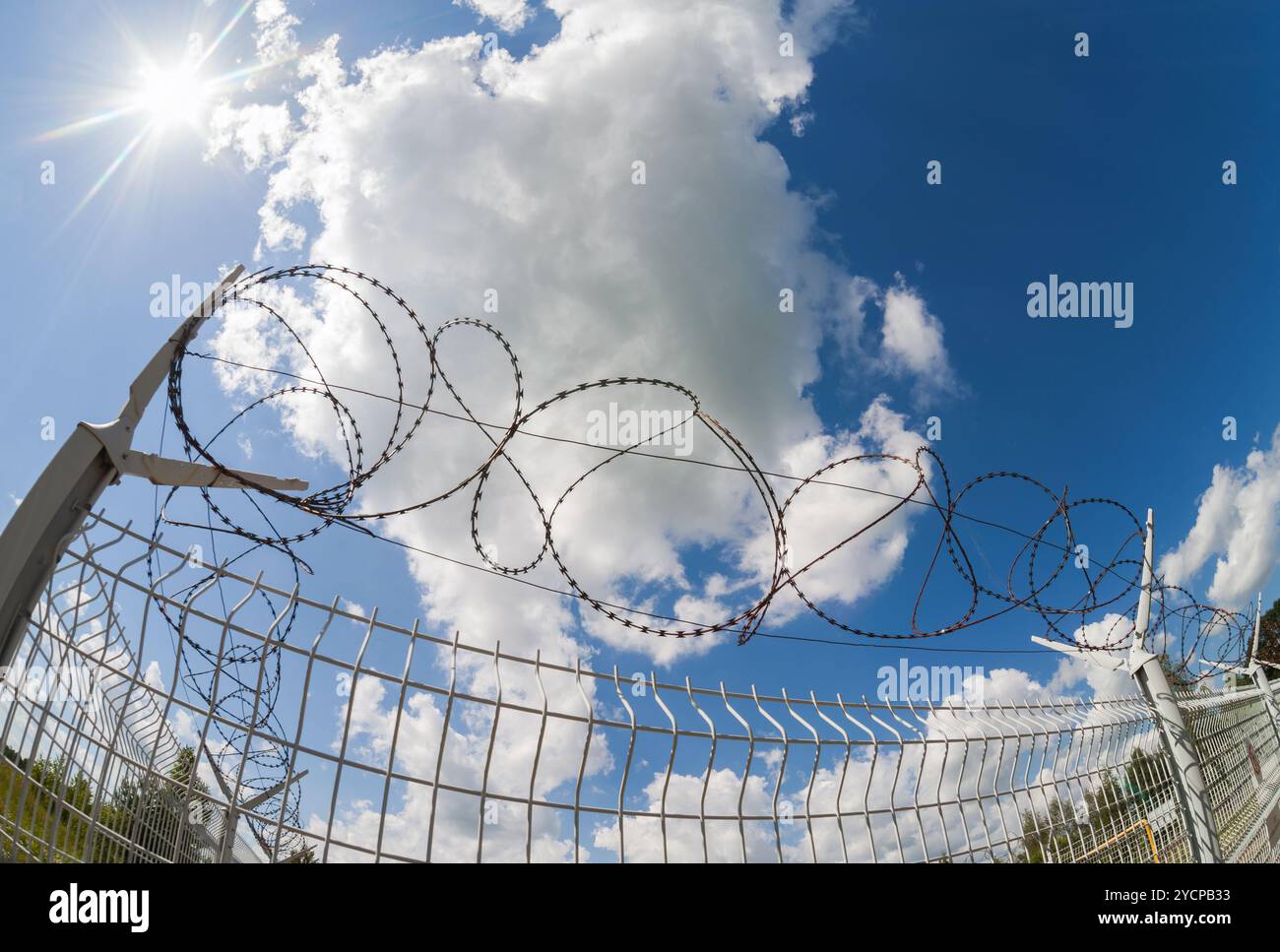 Fence with barbed wire on blue sky background Stock Photo - Alamy