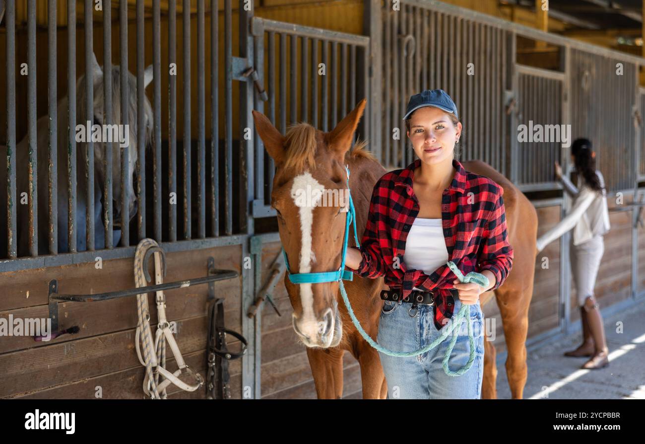 Young woman leads horse out of stable Stock Photo - Alamy