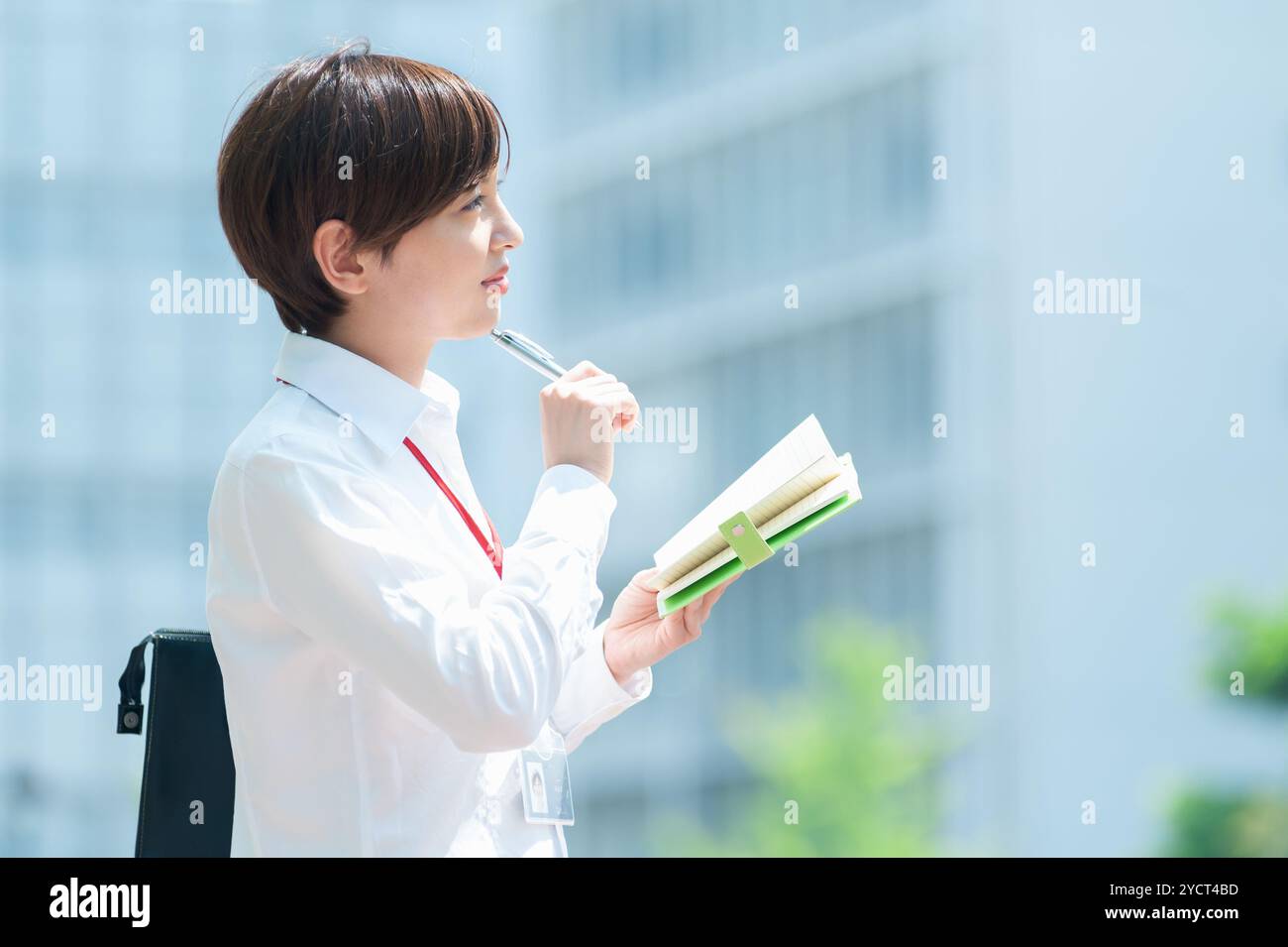 Office worker thinking while taking notes in notebook Stock Photo - Alamy