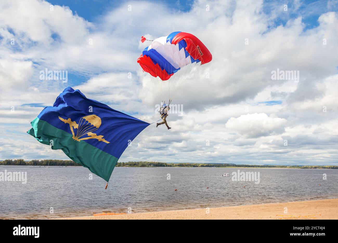 Single military parachute jumper on a  wing parachute execute a controlled descent by parachute hung with airborne flag Stock Photo
