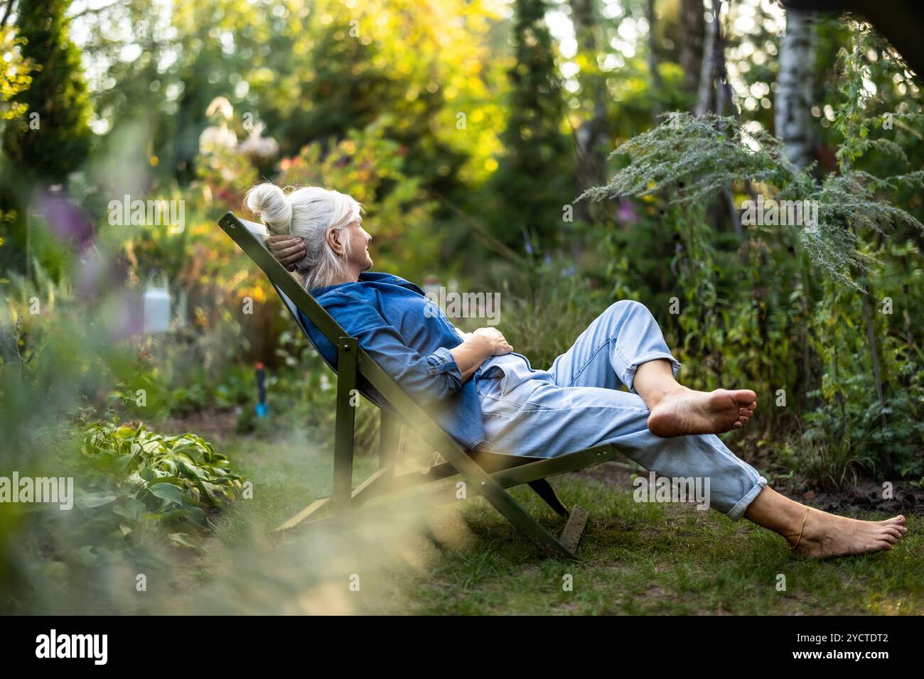 Mature woman relaxing in deckchair in her garden Stock Photo - Alamy