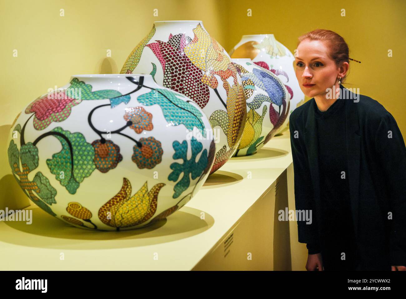 London, UK. 24th Oct, 2024. Staff pose with beautiful Fencai technique works at the Shirley Sherwood Gallery. Fencai is a Chinese technique where porcelain is decorated with an over-glaze enamel using opaque pastels to create imagery, here dots are intricately filled into the pattern,  for botanical motives. Expressions in Blue: Monumental Porcelain by Felicity Aylieff features 40 new works created especially for Kew. The exhibition runs from 26 October 2024 - 23 March 2025. Credit: Imageplotter/Alamy Live News Stock Photo