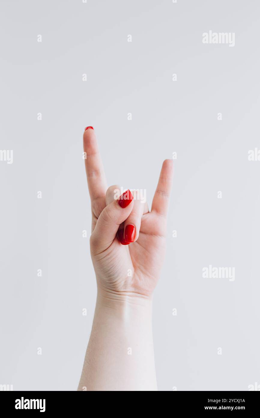 A close-up of a hand making the iconic rock and roll sign of the horns ...