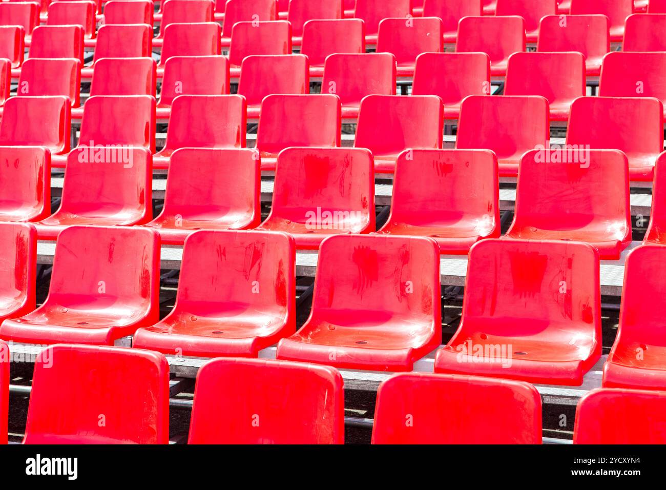 Rows empty bright red plastic seats in a stadium Stock Photo