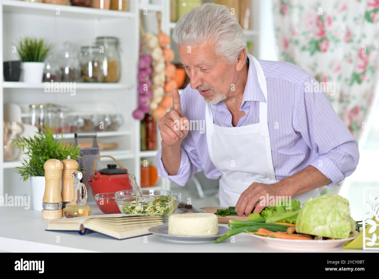 Elderly man in apron preparing healthy food at home Stock Photo