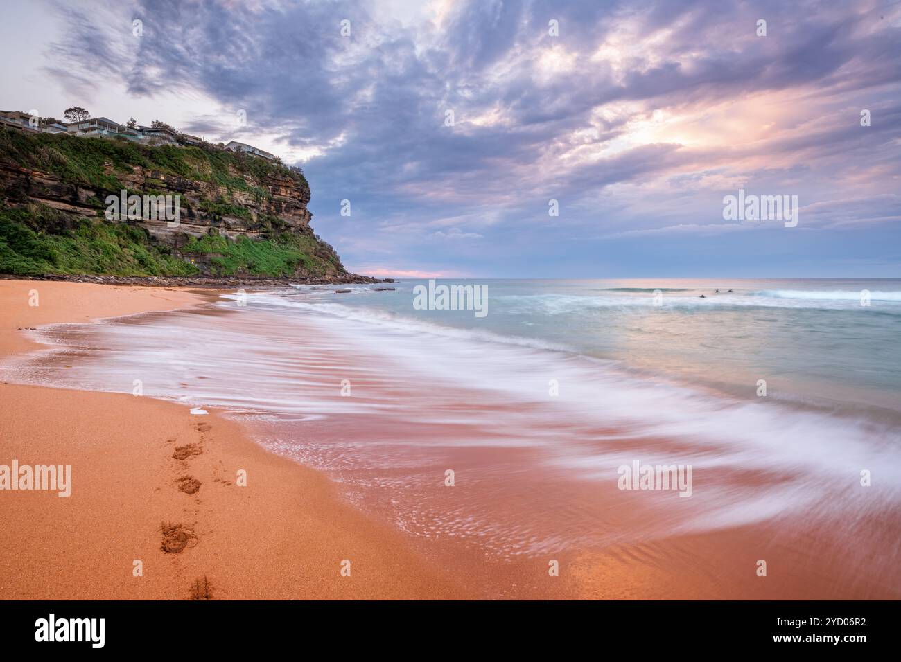 Waves wash on the seashore washing away footprints Stock Photo