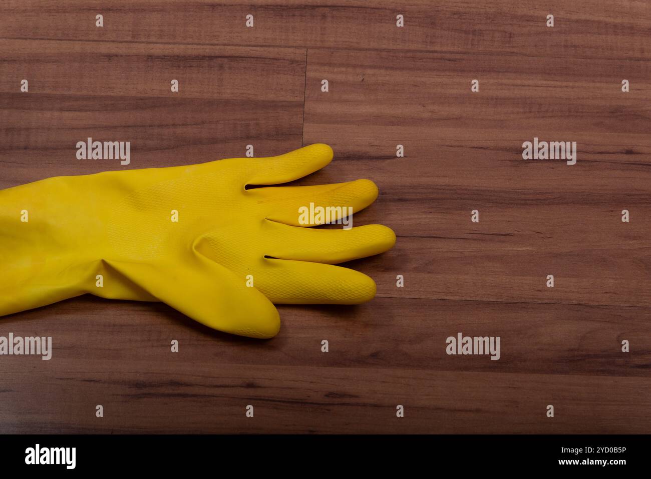 Pair of yellow rubber washing cleaning gloves isolated on wooden background. Stock Photo